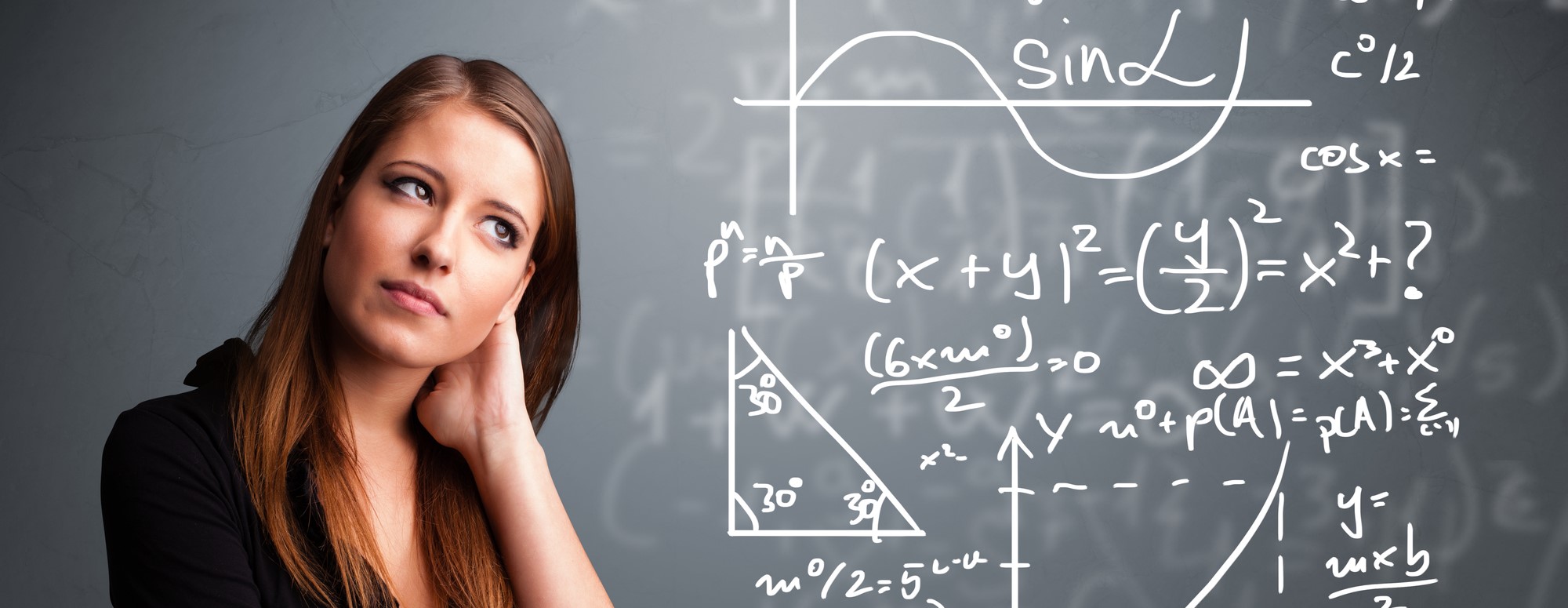 Young woman in a thoughtful pose standing in front of a blackboard that is covered in equations