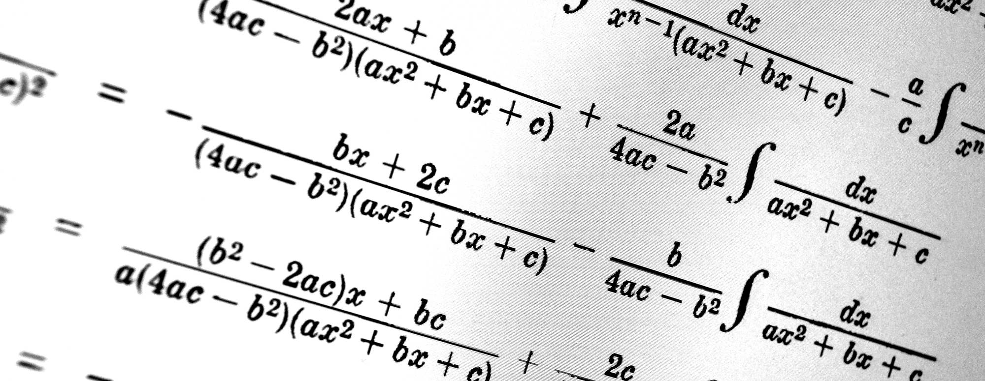 Young woman in a thoughtful pose standing in front of a blackboard that is covered in equations