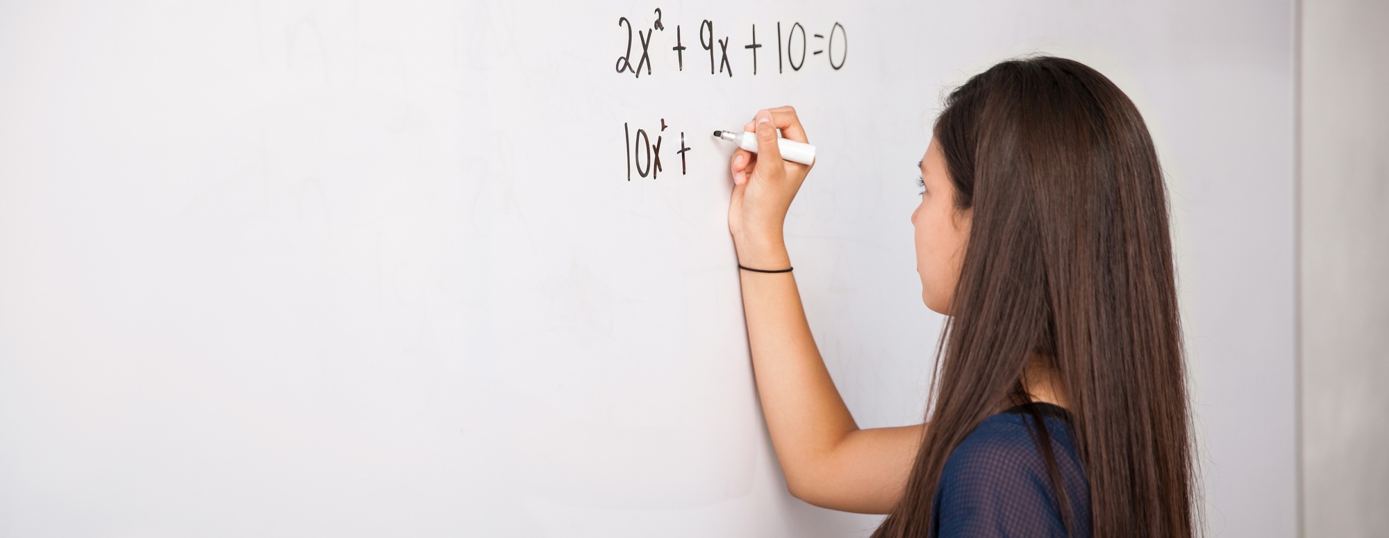 A girl is writing quadratic equations on a whiteboard.